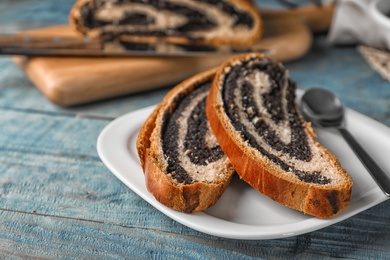 Photo of Cut tasty sweet bun with poppy seeds on wooden table