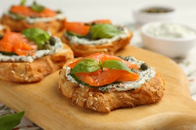 Photo of Tasty canapes with salmon, capers, cucumber and sauce on table, closeup