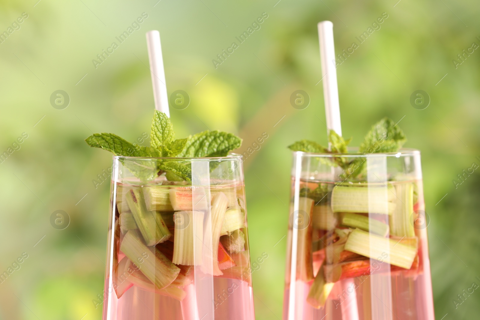 Photo of Glasses of tasty rhubarb cocktail outdoors, closeup