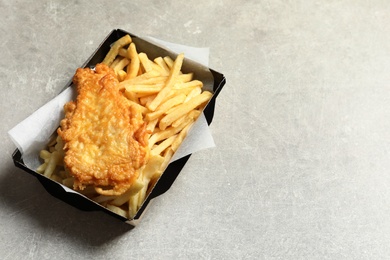 Photo of Disposable container with British Traditional Fish and potato chips on grey background. Space for text