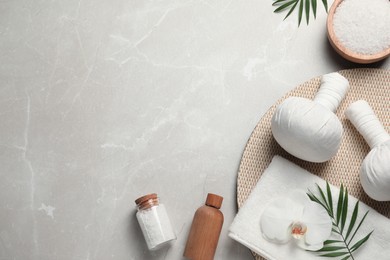 Photo of Flat lay composition with herbal massage bags and other spa products on light grey marble table. Space for text