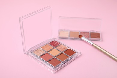 Photo of Beautiful eye shadow palettes and brush on pink background