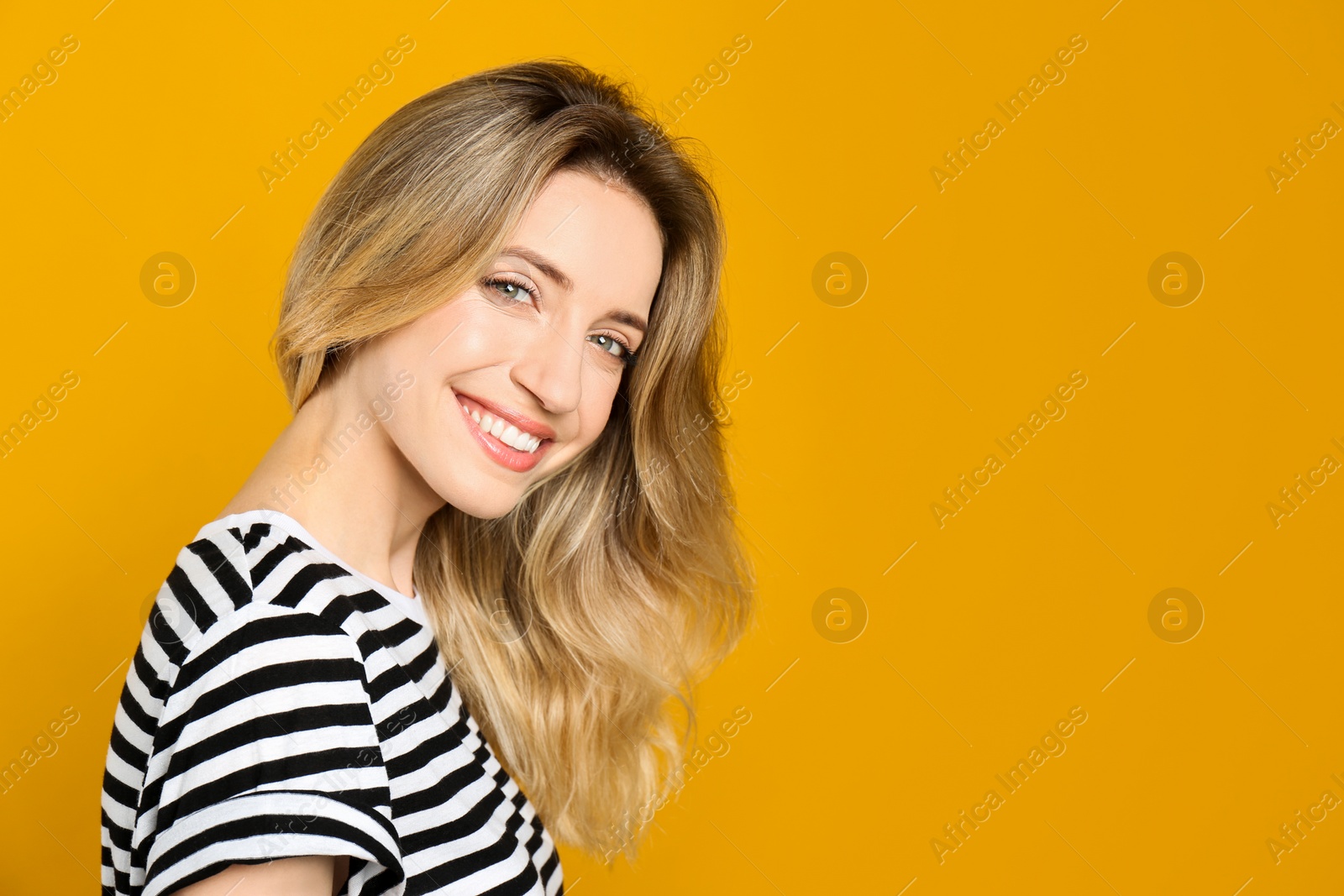 Photo of Portrait of happy young woman with beautiful blonde hair and charming smile on yellow background. Space for text