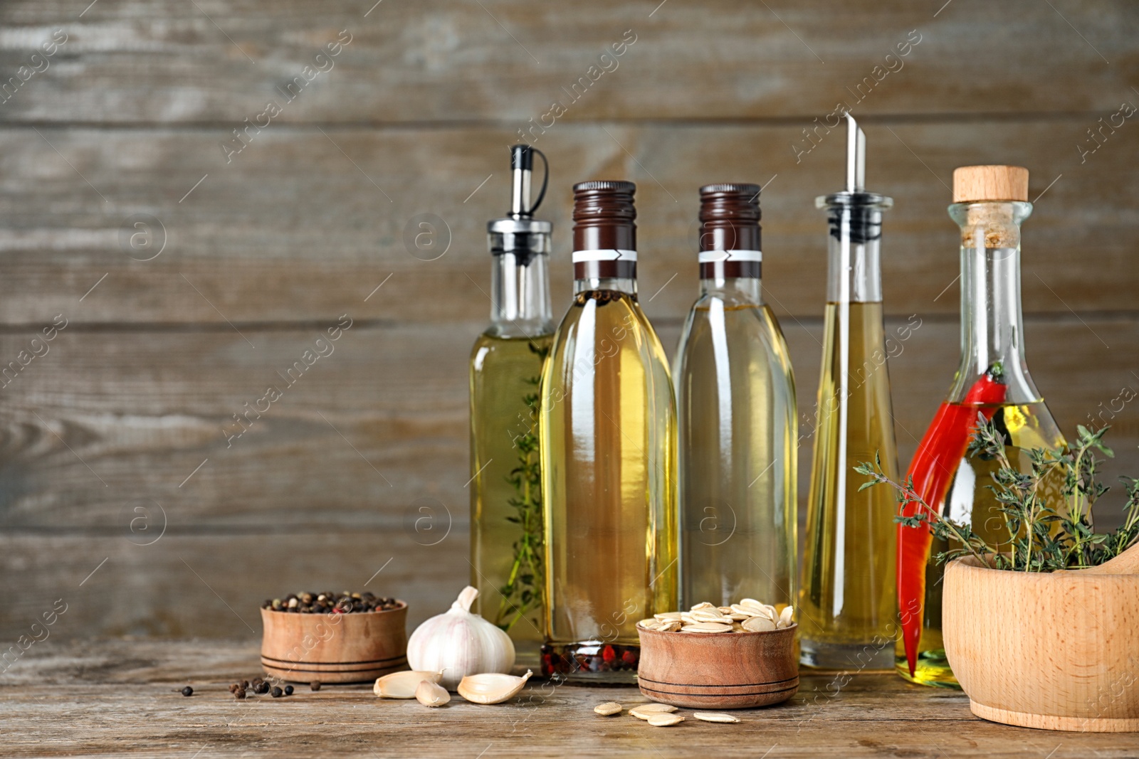 Photo of Different cooking oils in bottles on wooden table