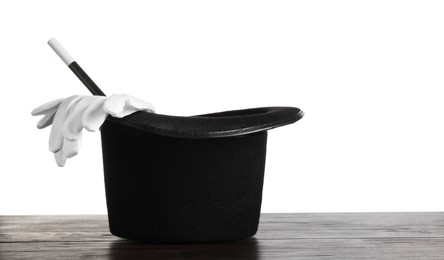 Photo of Magician's hat, gloves and wand on wooden table against white background