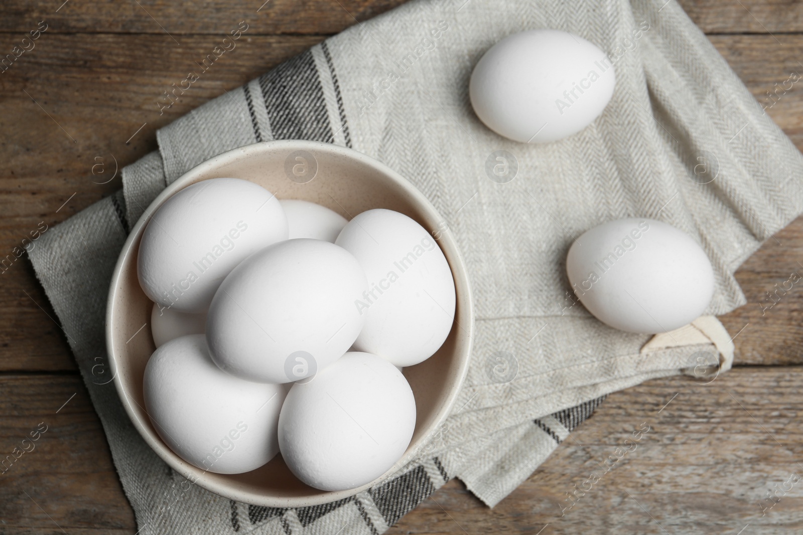 Photo of Many fresh raw chicken eggs in bowl on wooden table, flat lay