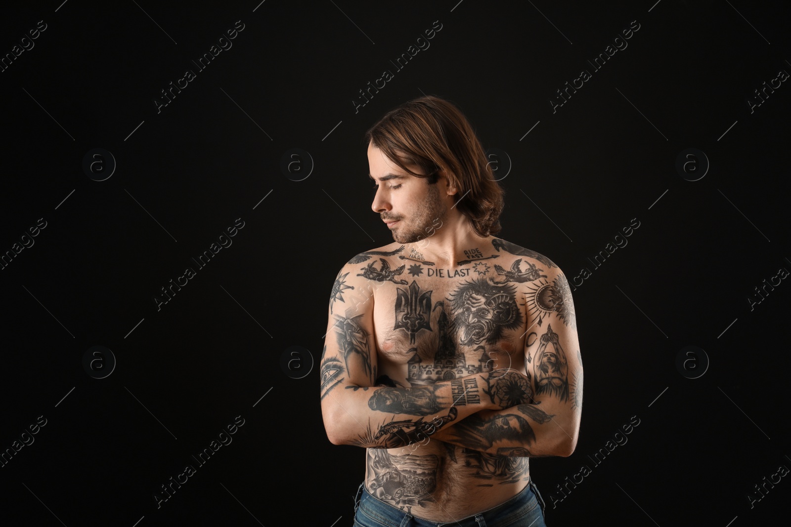 Photo of Young man with tattoos on body against black background