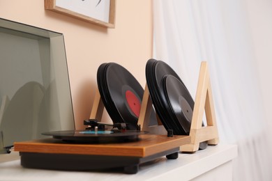 Vinyl records and player on white wooden table indoors