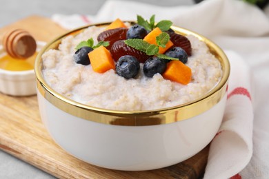 Photo of Delicious barley porridge with blueberries, pumpkin, dates and mint in bowl on table, closeup