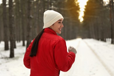 Happy woman running in winter forest. Outdoors sports exercises