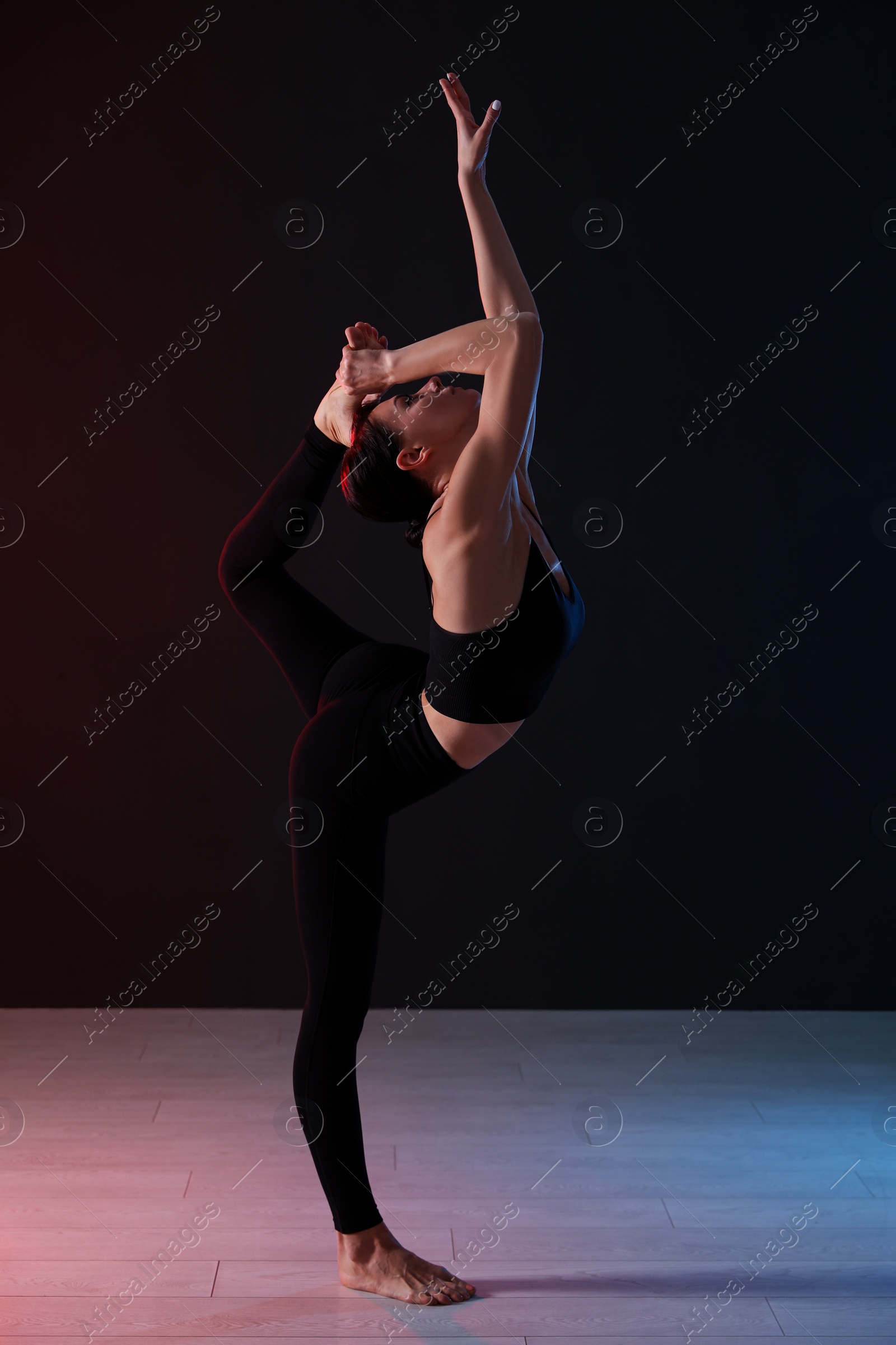 Photo of Young professional acrobat exercising in dark studio