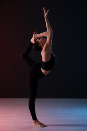 Young professional acrobat exercising in dark studio