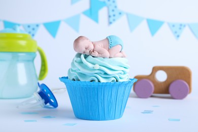 Photo of Beautifully decorated baby shower cupcake for boy with cream and topper on light background.