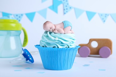 Beautifully decorated baby shower cupcake for boy with cream and topper on light background.