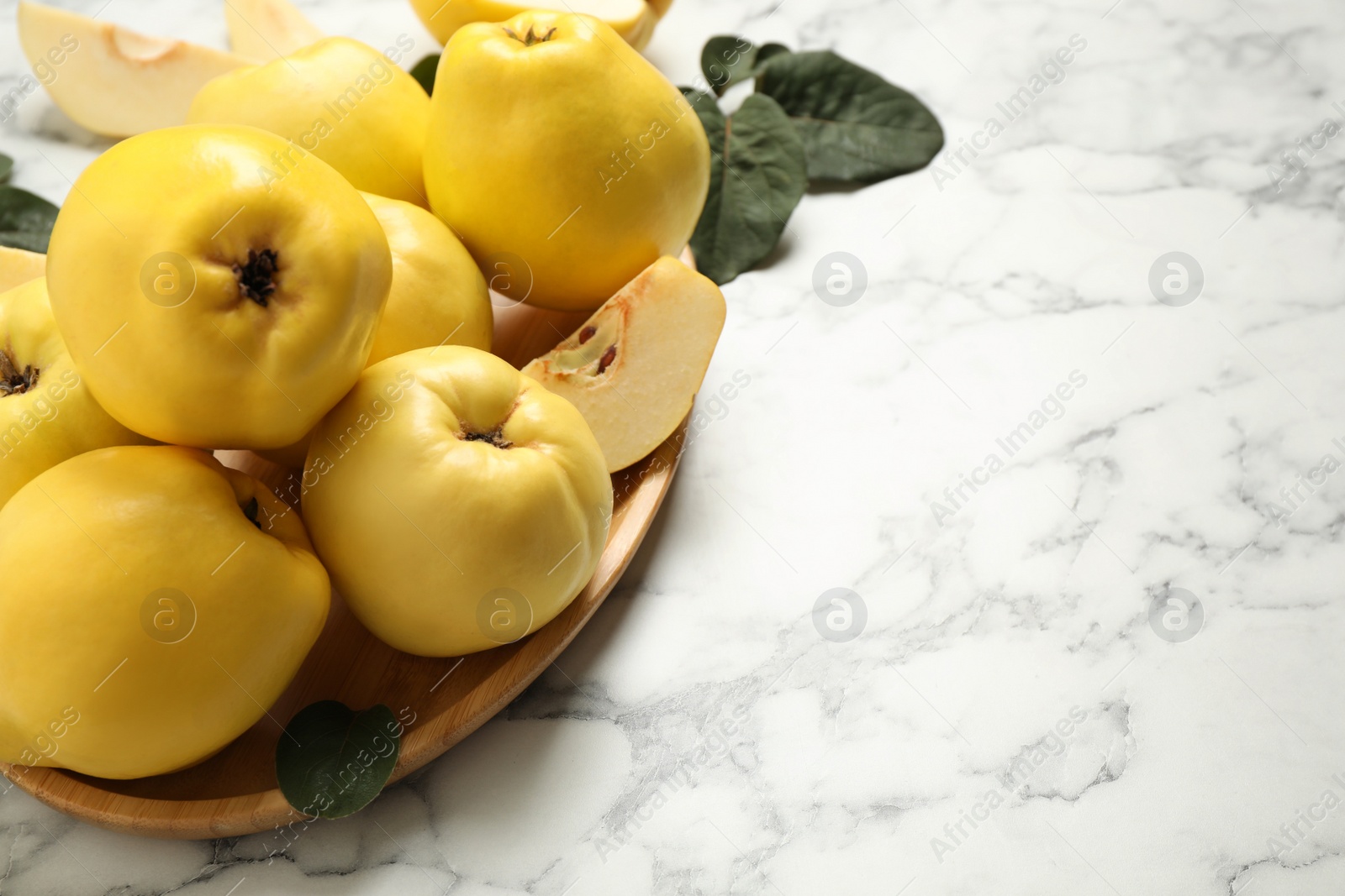 Photo of Fresh ripe organic quinces on white marble table. Space for text