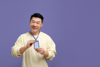 Photo of Happy asian man with vip pass badge on purple background. Space for text