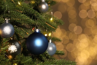 Beautiful baubles hanging on Christmas tree against blurred festive lights, closeup. Space for text