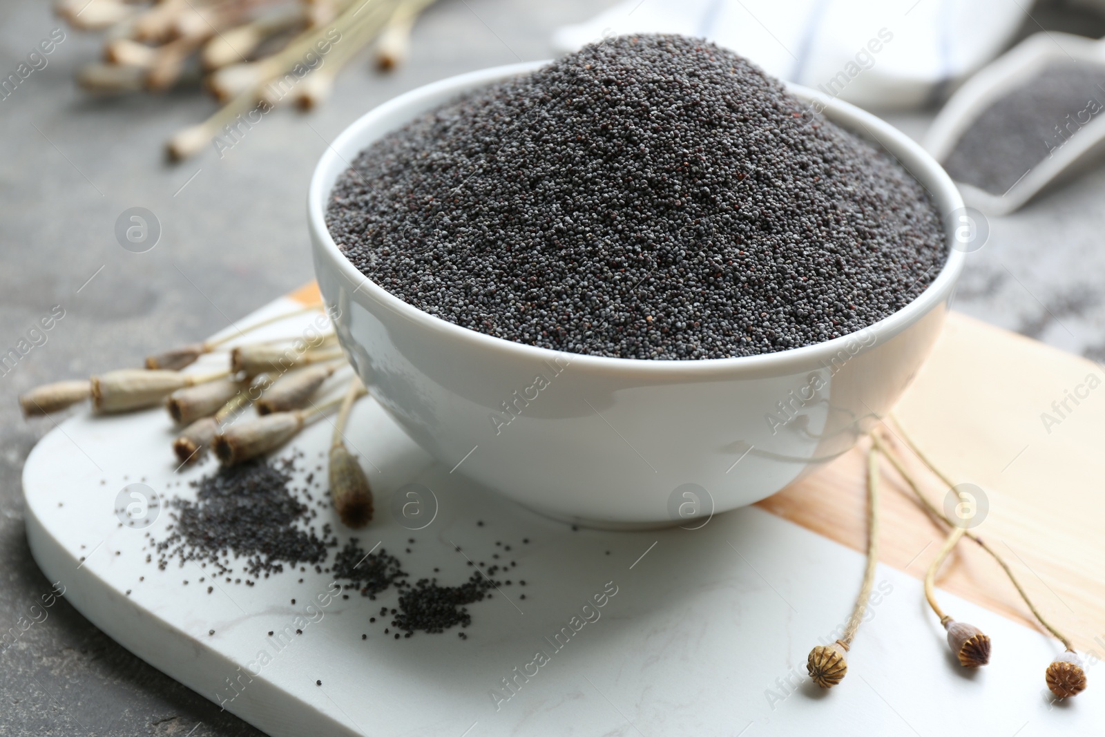 Photo of Dried poppyheads and bowl with seeds on table