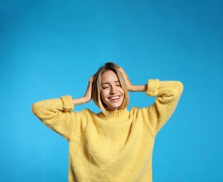 Photo of Beautiful young woman wearing knitted sweater on light blue background