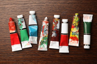Tubes with oil paints on wooden table, flat lay