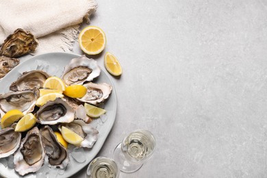 Photo of Fresh oysters with lemon and glasses of champagne on grey table, flat lay. Space for text
