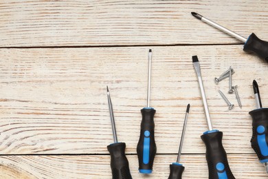 Set of screwdrivers and screws on wooden table, flat lay. Space for text