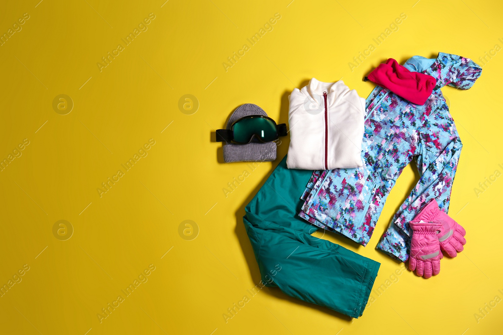 Photo of Stylish winter sport clothes on yellow background, flat lay. Space for text