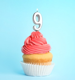 Birthday cupcake with number nine candle on blue background