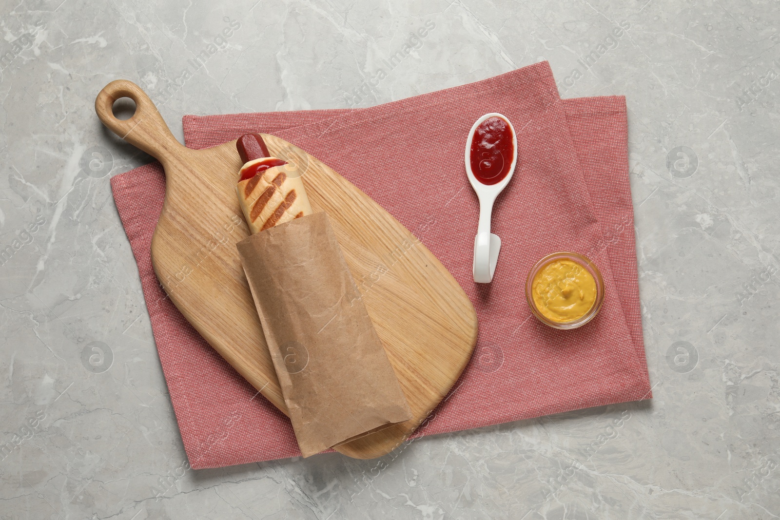 Photo of Delicious french hot dog and dip sauces on grey table, top view