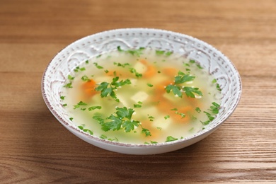 Photo of Bowl of fresh homemade soup to cure flu on wooden background