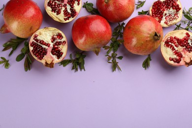 Flat lay composition with ripe pomegranates on violet background. Space for text