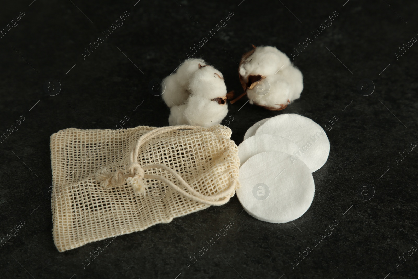 Photo of Cotton pads, bag and flowers on black table