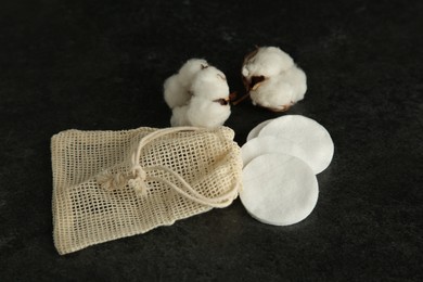 Photo of Cotton pads, bag and flowers on black table