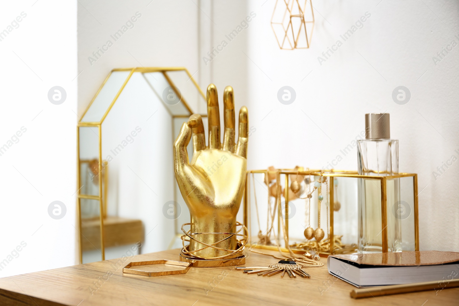 Photo of Composition with gold accessories on dressing table near white wall