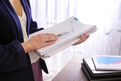 Photo of Businesswoman with stack of documents at workplace, closeup