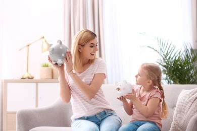Photo of Mother and daughter with piggy banks at home