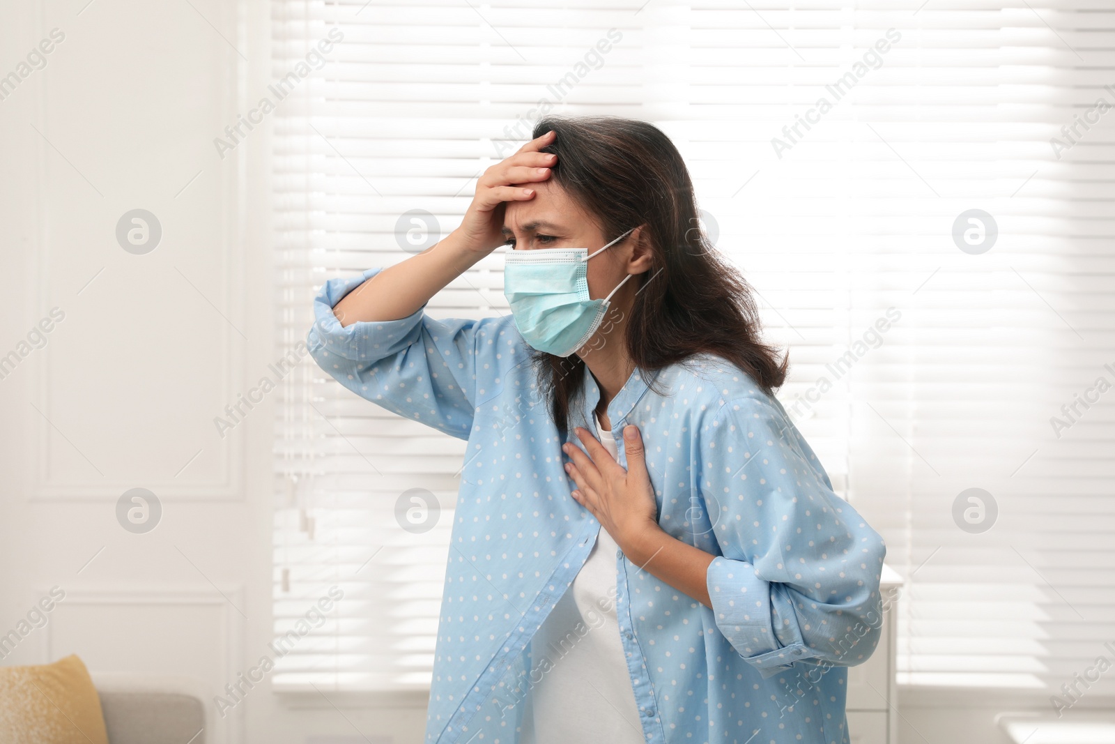 Photo of Mature woman with protective mask suffering from breathing problem at home
