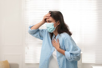 Photo of Mature woman with protective mask suffering from breathing problem at home