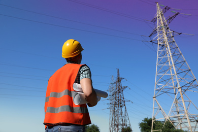 Photo of Professional electrician with papers near high voltage tower