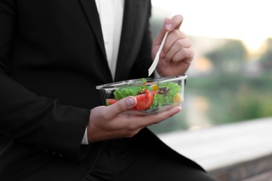 Photo of Businessman eating from lunch box outdoors, closeup