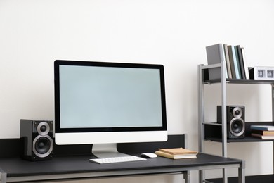 Photo of Modern computer with audio speakers on table indoors