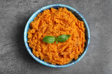 Photo of Bowl of tasty sweet potato puree on grey table, top view