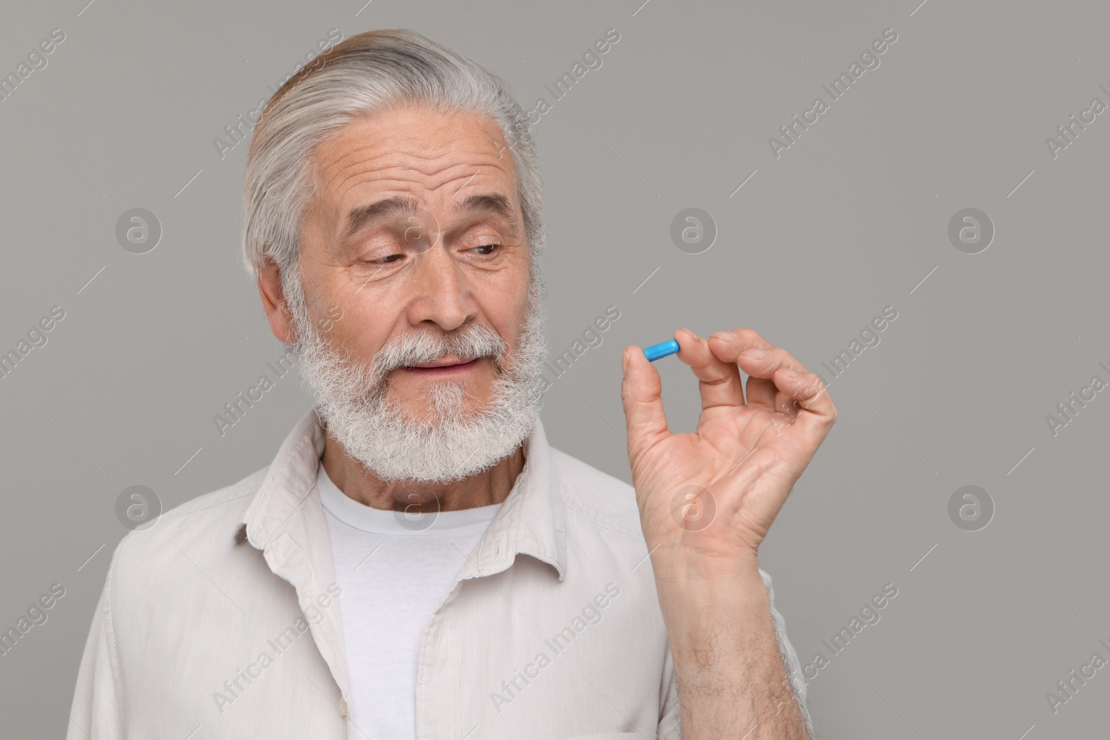 Photo of Senior man with pill on grey background