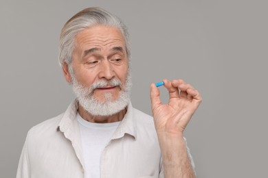 Photo of Senior man with pill on grey background