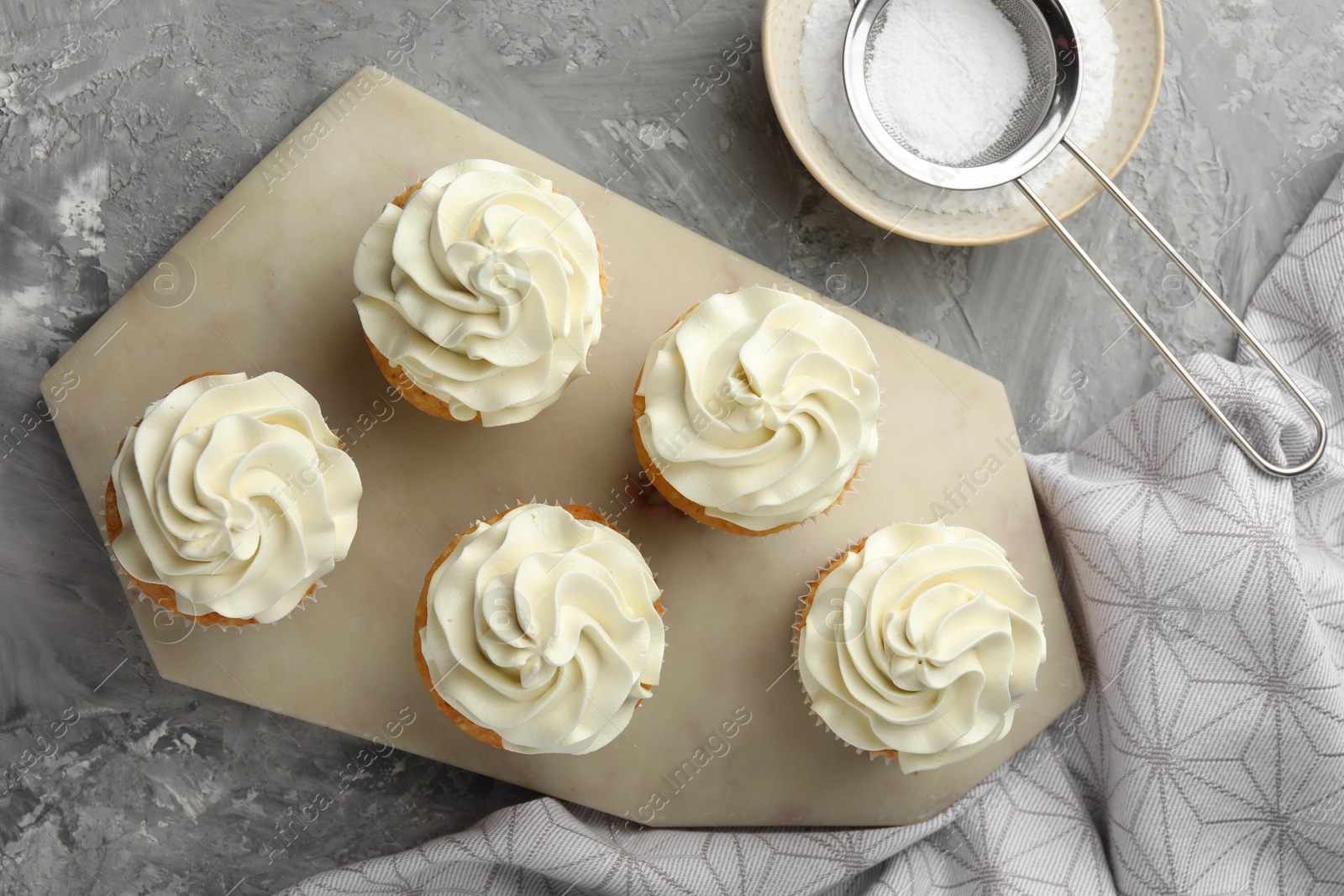 Photo of Tasty cupcakes with vanilla cream on grey table, top view