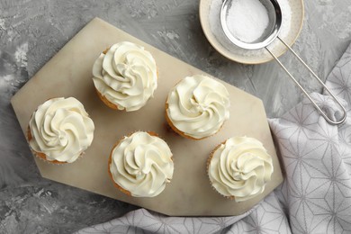 Photo of Tasty cupcakes with vanilla cream on grey table, top view