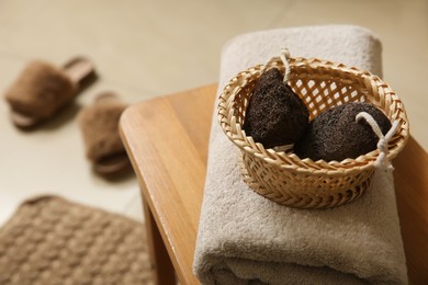 Photo of Pumice stones in wicker basket and towel on table indoors. Space for text
