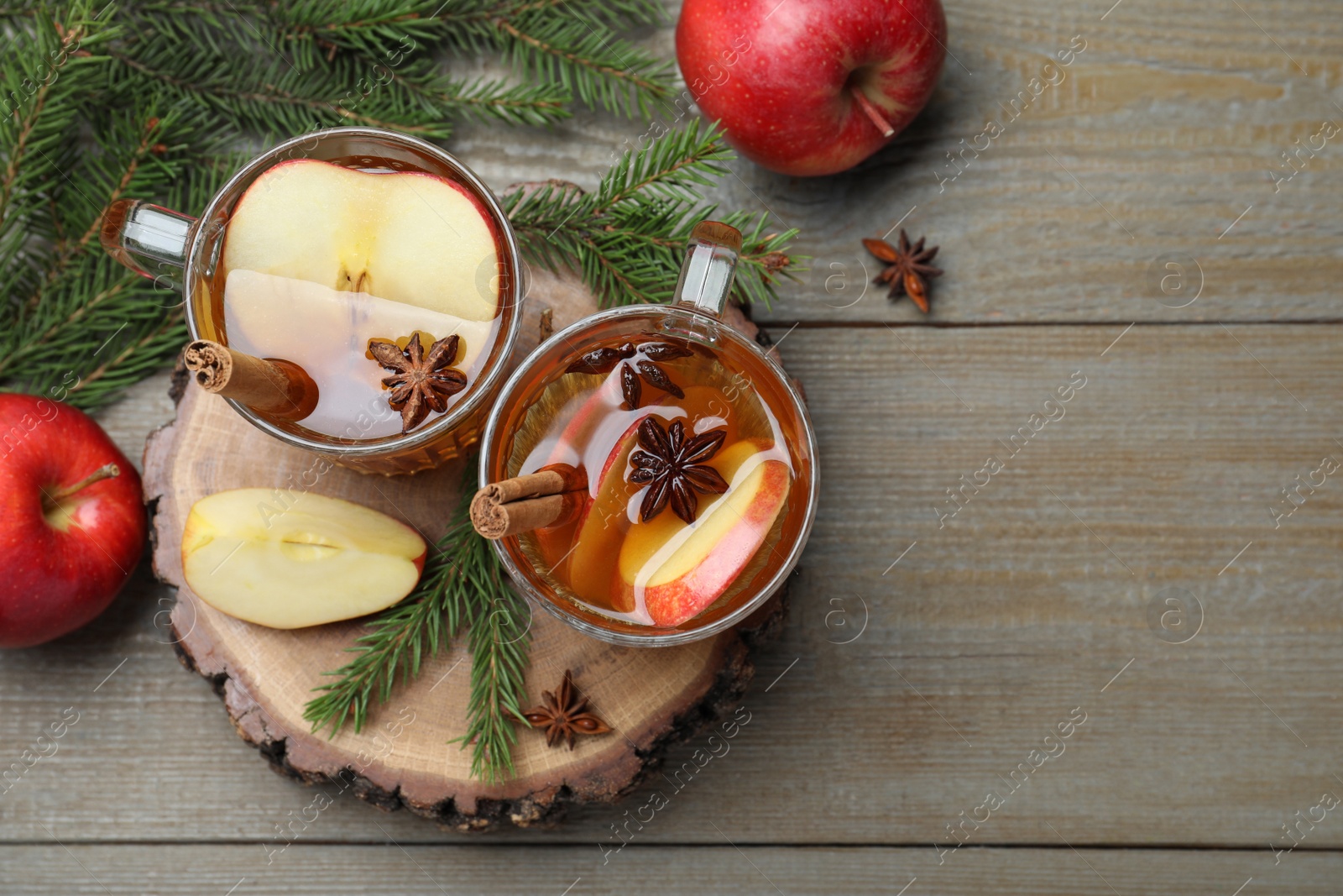 Photo of Hot mulled cider, fresh fruits and fir branches on wooden table, flat lay. Space for text