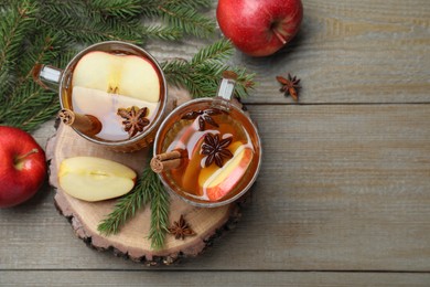 Hot mulled cider, fresh fruits and fir branches on wooden table, flat lay. Space for text
