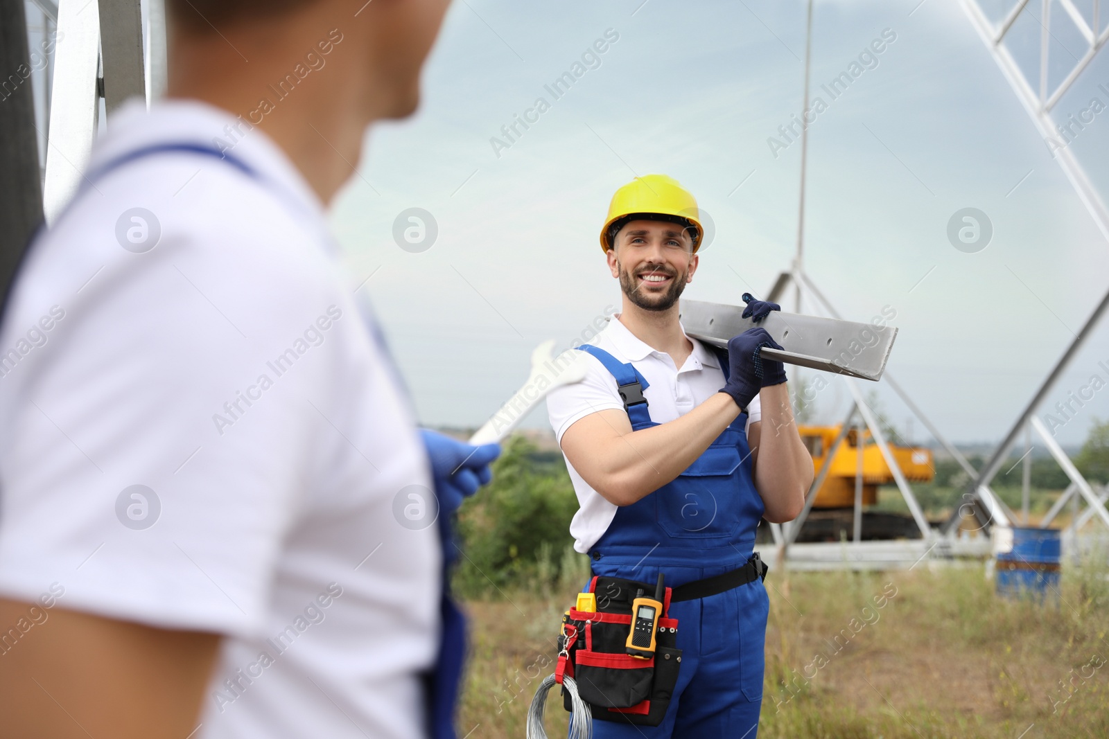 Photo of Workers building high voltage tower construction outdoors. Installation of electrical substation